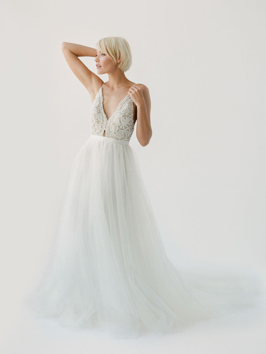 Champagne-toned wedding dress with white beading, an open back, and a soft princess tulle skirt
