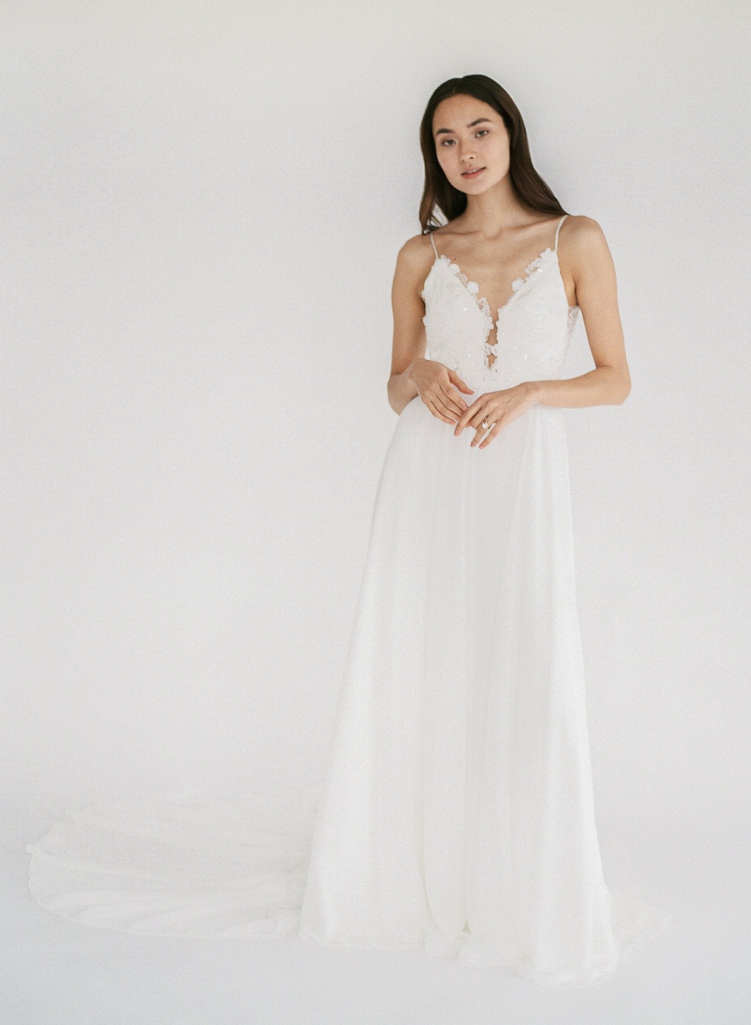 Flowy beach wedding dress with lace appliqué, a low back, and plunging neckline