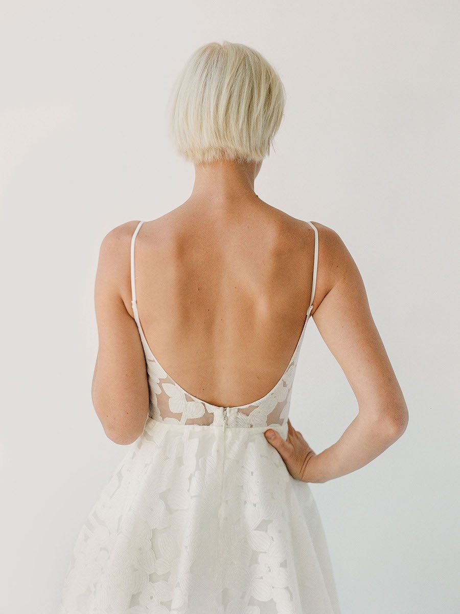 Simple and effortless wedding gown with sheer floral lace, a long train, and a low scoop back