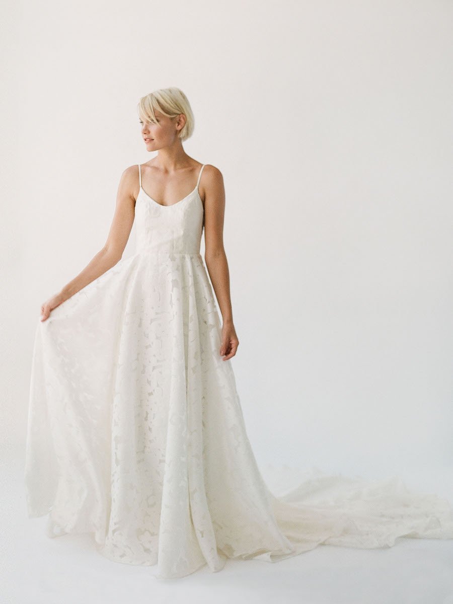 Simple and effortless wedding gown with sheer floral lace, a long train, and a low scoop back