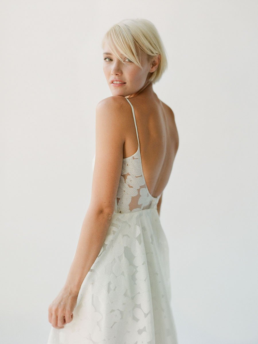 Simple and effortless wedding gown with sheer floral lace, a long train, and a low scoop back