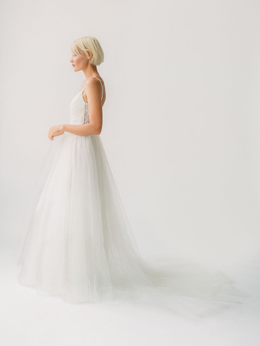 Low back wedding gown with a plunging beaded neckline and a princess tulle skirt