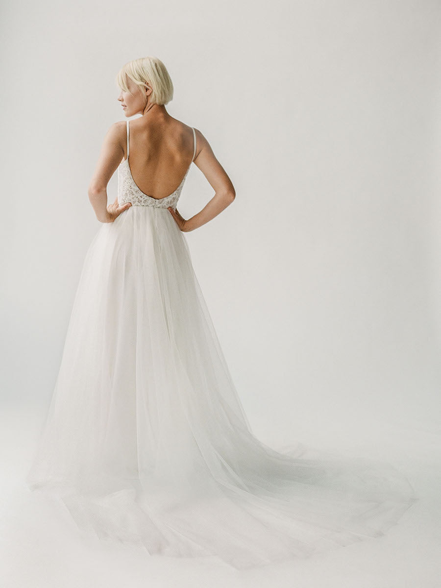 Low back wedding gown with a plunging beaded neckline and a princess tulle skirt